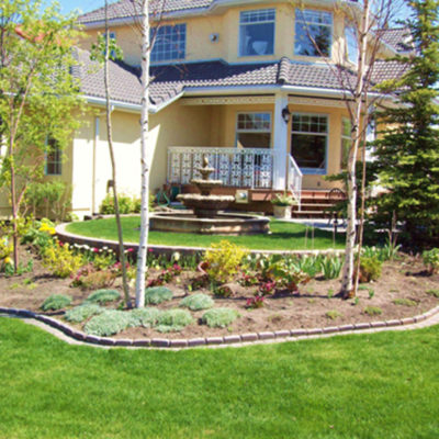 Backyard Oasis Yellow House by European Garden Design Calgary
